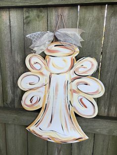 an angel ornament hanging on a wooden fence