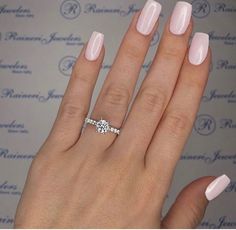 a woman's hand with a pink manicured nail polish and a diamond ring