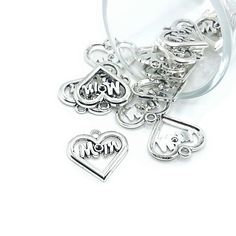 three charms with the word mom and two heart shaped ones in silver on a white background