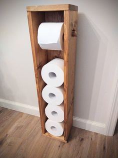 two rolls of toilet paper are in a wooden box on the floor next to a wall