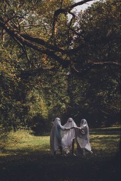 two ghostly people standing in the grass under trees