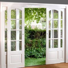 an open white door leading to a lush green yard with trees in the back ground