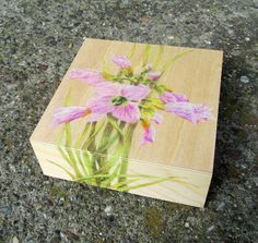 a wooden box with flowers painted on the front and side, sitting on concrete ground