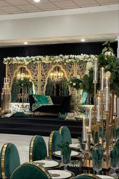 an elaborately decorated stage set up with green chairs and white flowers on the table