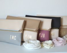 five bags with monogrammed letters on them sitting on a table next to flowers