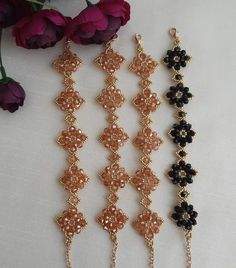 three necklaces with black and orange beads on them next to flowers in the background