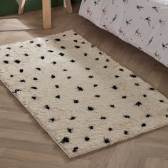 a white rug with black spots on it in a bedroom next to a wooden floor