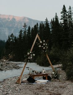 an outdoor ceremony setup with flowers and greenery on the ground in front of mountains