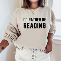 a woman wearing a sweatshirt that says i'd rather be reading