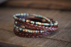 three bracelets with beads and leather cords on a wooden table, close up view