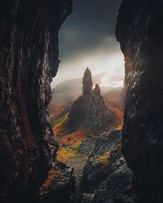 an image of some mountains taken from inside a cave with the sun coming through it