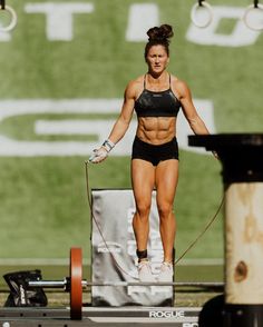 a woman standing on top of a metal bar in front of a green grass covered field