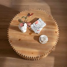 a wooden table topped with two white cups and saucers