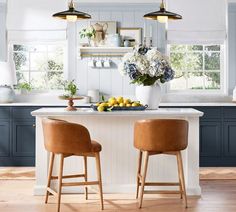 two stools sit at the center of a kitchen island in front of blue cabinets