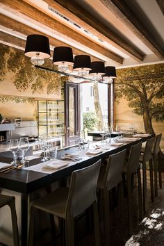 a long dining table with place settings in front of a tree painted on the wall