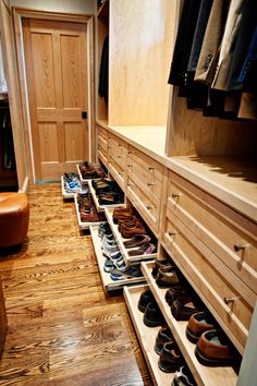 an organized closet with wooden drawers and shoes