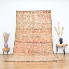 an old rug is sitting on the floor in front of a table with two vases