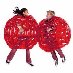 two people in red costumes are holding large plastic objects with their arms and legs spread out