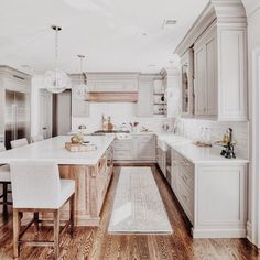 a large kitchen with wooden floors and white cabinets on the walls, along with an island in the middle