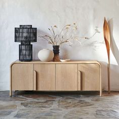 two vases sitting on top of a wooden cabinet in front of a white wall