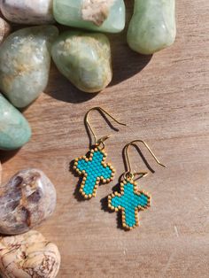 a pair of earrings sitting on top of a wooden table next to rocks and stones