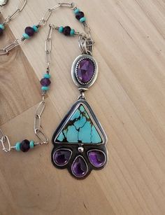 Turquoise and amethyst.  This is constructed from 925 sterling silver.  I have chosen a beautiful genuine triangle shape turquoise for this statement piece. The color in this stone is phenomenal.  I  paired the turquoise with beautiful amethyst.  The top amethyst is a faceted stone.  And the teardrops are a fantastic smooth finish.  And to make this piece personal,  I have created the chain.  Incorporating tiny Pilot Mountain turquoise rondels on each side of faceted amythest beads.  This is a g Southwestern Style Purple Jewelry For Gift, Turquoise Amethyst Necklace With Natural Stones, Purple Southwestern Jewelry For Gift, Purple Southwestern Style Jewelry For Gift, Purple Southwestern Jewelry For Gifts, Turquoise Triangle Jewelry For Gifts, Turquoise Triangle Jewelry Gift, Bohemian Turquoise Jewelry With Amethyst, Purple Teardrop Multi-stone Jewelry