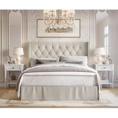 a white bed sitting in a bedroom next to two lamps and a chandelier