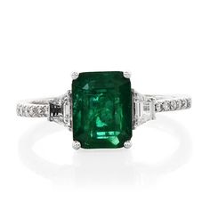 an emerald and diamond ring on a white background