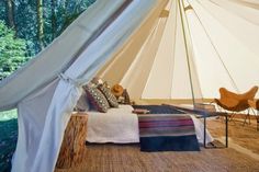 a bed sitting inside of a white tent next to a wooden table and two chairs