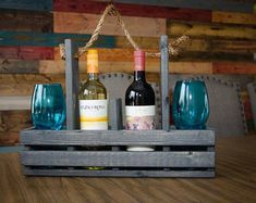 three bottles of wine sitting on top of a wooden crate next to two empty glasses