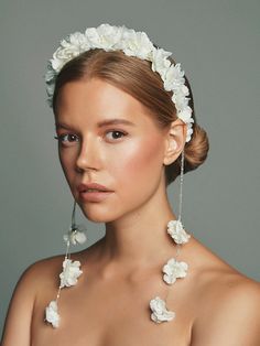 a woman with flowers in her hair wearing a necklace and earring made out of pearls