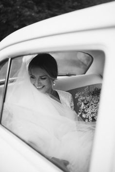 a woman in a wedding dress sitting in a car