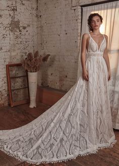 a woman standing in front of a brick wall wearing a white wedding dress with an open back