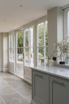 an empty kitchen with large windows and tile flooring