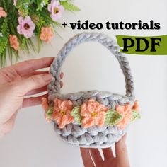 a crocheted basket is being held by someone's hand with flowers on it