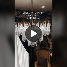 a chandelier hanging from the ceiling in front of a window with curtains on it