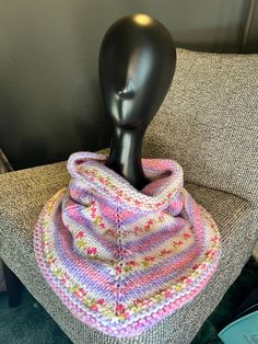 a mannequin's head sitting on a chair with a knitted scarf around it