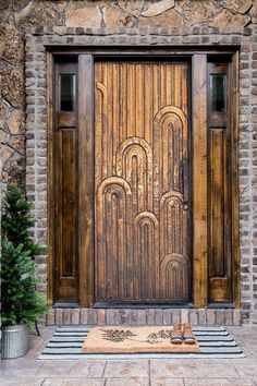 a wooden door is shown in front of a stone building with potted plants on the side