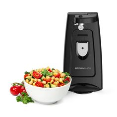 a bowl of salad next to a black kitchen appliance on a white background