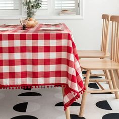 a red and white checkered table cloth with pom poms sits on a wooden chair