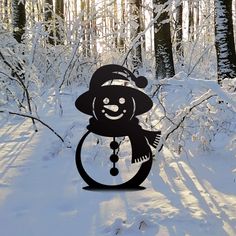 a snowman with a hat and scarf on standing in the middle of a snowy forest