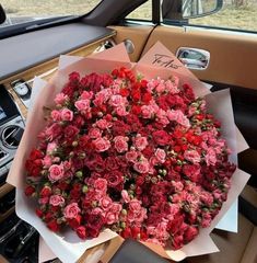 a large bouquet of red roses is in the back seat of a car, ready to be delivered