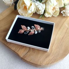 a white box with some flowers in it on top of a wooden table next to roses