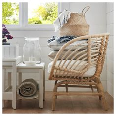 a wicker chair sitting in front of a window next to a table with baskets on it