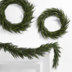 two green wreaths hanging from the side of a white wall