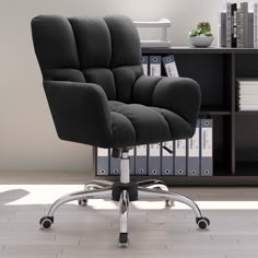 a black office chair sitting on top of a hard wood floor next to a book shelf