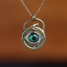 The Eye Inside The Snake, Snake Entwined Eye Necklace, Anaconda's Green Eye Necklace, Eyes Of Reptiles, 925K Sterling Silver Pendant, Gift My eye designs can be made specifically for your eyes, you need to take a beautiful iris photo for us. Then we can customize it for you. You can also add or remove blood details to our eye designs. You can write this in the order notes. Please send me a message after ordering. I can do as you wish. A quasi-universal symbol of protection, the evil eye is refer One Of A Kind Symbolic Sterling Silver Jewelry, Antique Sterling Silver Hand Forged Necklaces, Antique Hand Forged Sterling Silver Necklaces, Antique Hand Forged Sterling Silver Necklace, Eye Designs, Luxury Jewelry Box, Green Eye, The Snake, Eye Design