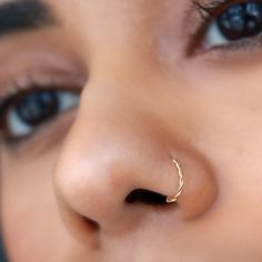 a close up of a person's nose with a gold nose ring on it