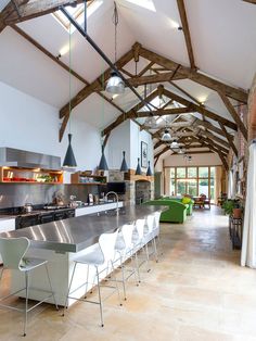 an open kitchen and living room with exposed beams in the ceiling, along with white chairs