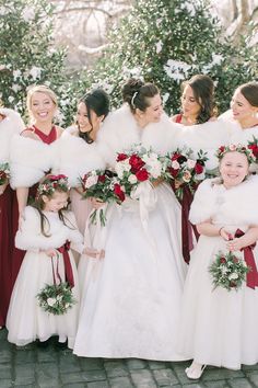 a group of bridesmaids in red dresses and fur stoles pose for a photo